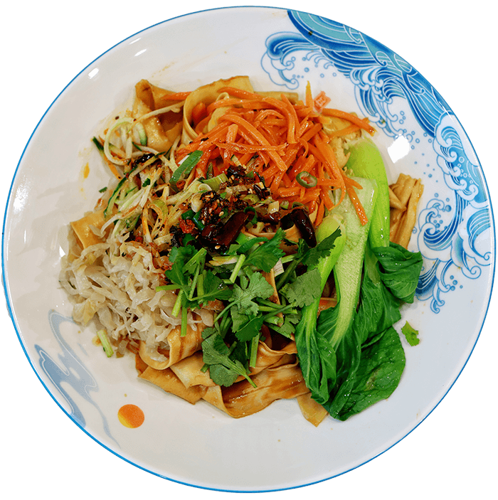 Weiße Schüssel von oben zeigend mit Nudeln, Karotten, Pak Choi und weiterem Gemüse